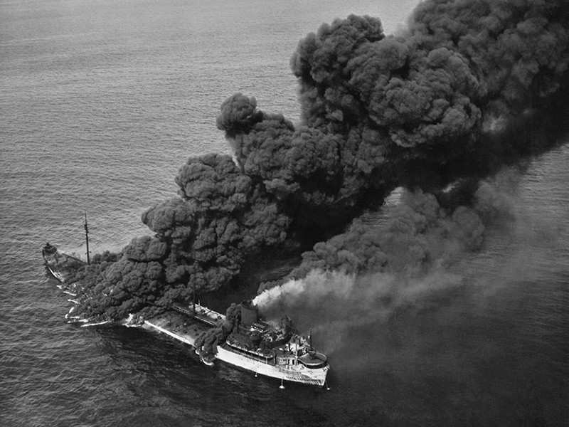 Black and white photograph of a boat on fire.