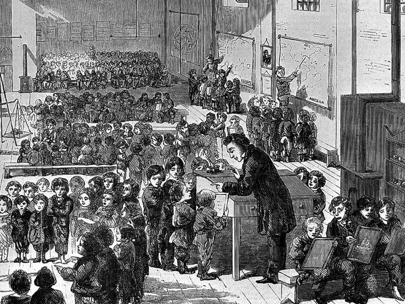An engraving of Ragged School, Whitechapel. A very large school room full of children, with a teacher at the front presiding over a wooden desk
