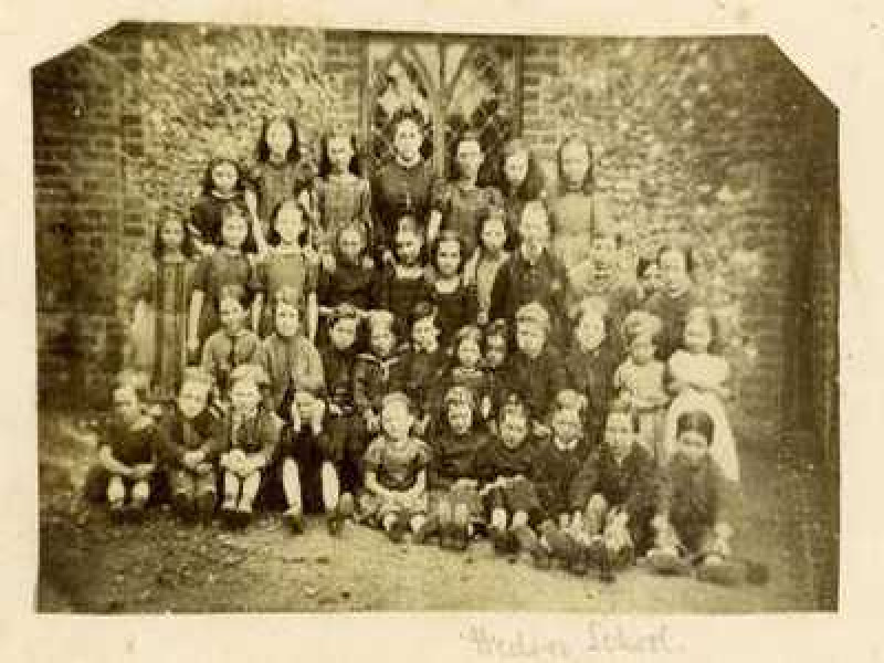 An aged photograph of a class of young school children.