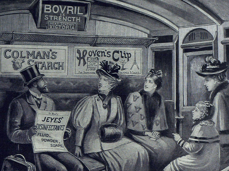 A man, three women, and a child sit in a carriage, all looking up at three advertisements on the wall behind them.