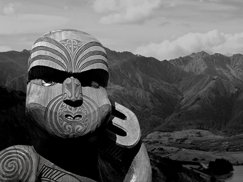 An image of a Māori statue, created by Māori people, who are the indigenous Polynesian people of mainland New Zealand. Behind the statue is a mountain range.