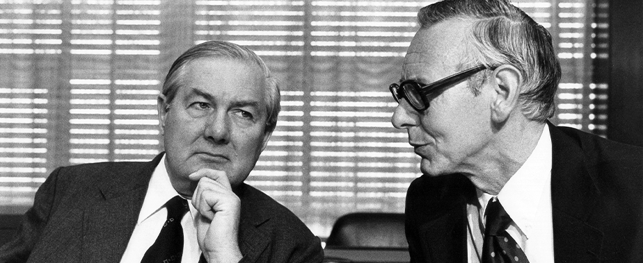 This is an image of James Callaghan, British Secretary of State for Foreign and Commonwealth Affairs, on the left, and Max van der Stoel, Dutch Minister for Foreign Affairs, on the right. The men are both dressed in suits and are engaging in conversation. Photo taken 1975.