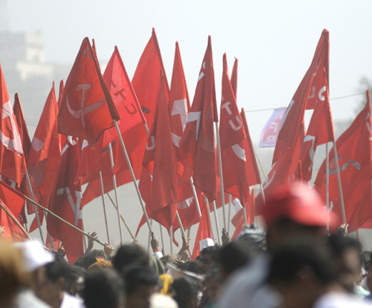 A crowd of people holding up the Communist Party of India flags.