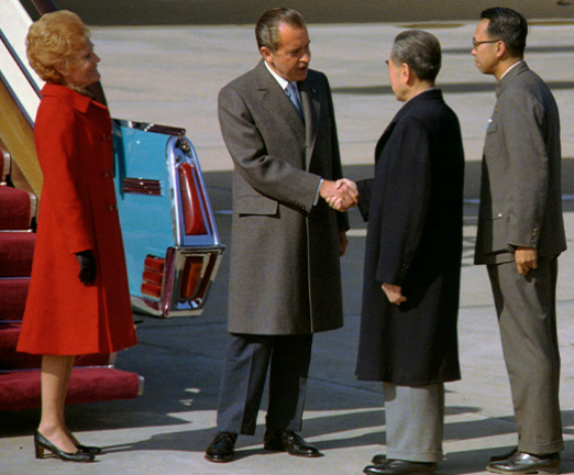 A photograph of Nixon visiting China. There are four people stood by the stairway of a plane.