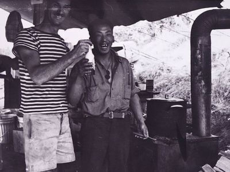 Black and white photograph of two men laughing while holding a bottle.