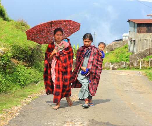 A photograph of Khasi tribal women carrying children on their back. One woman carries a large parasol.