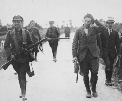 A photograph of an IRA prisoner under escort by National Army troops during the Civil War.