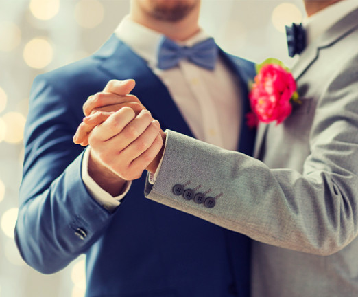 Photograph of two men dressed in suits dancing together. Only their torsos are visible.