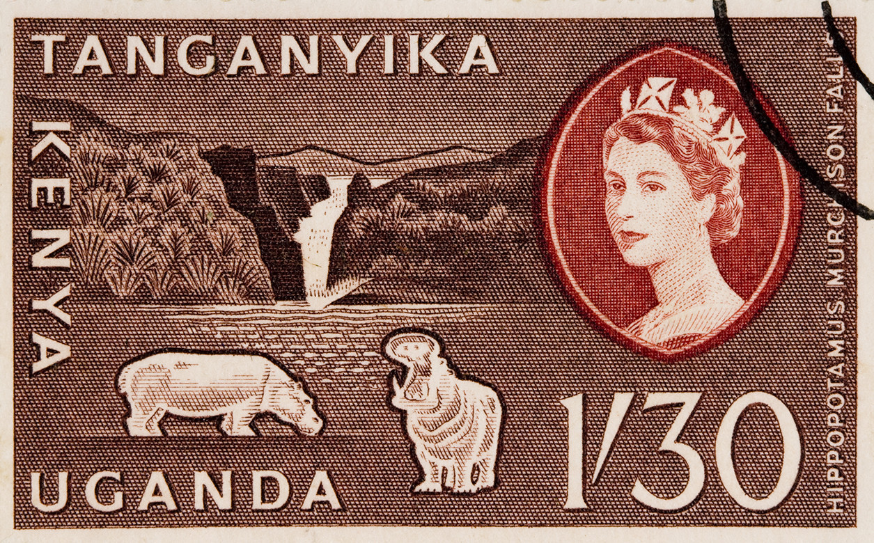 A stamp showing the Queen's head, a waterfall, and two drawings of hippos. The countries Tangantika, Kenya, and Uganda are printed on the stamp.
