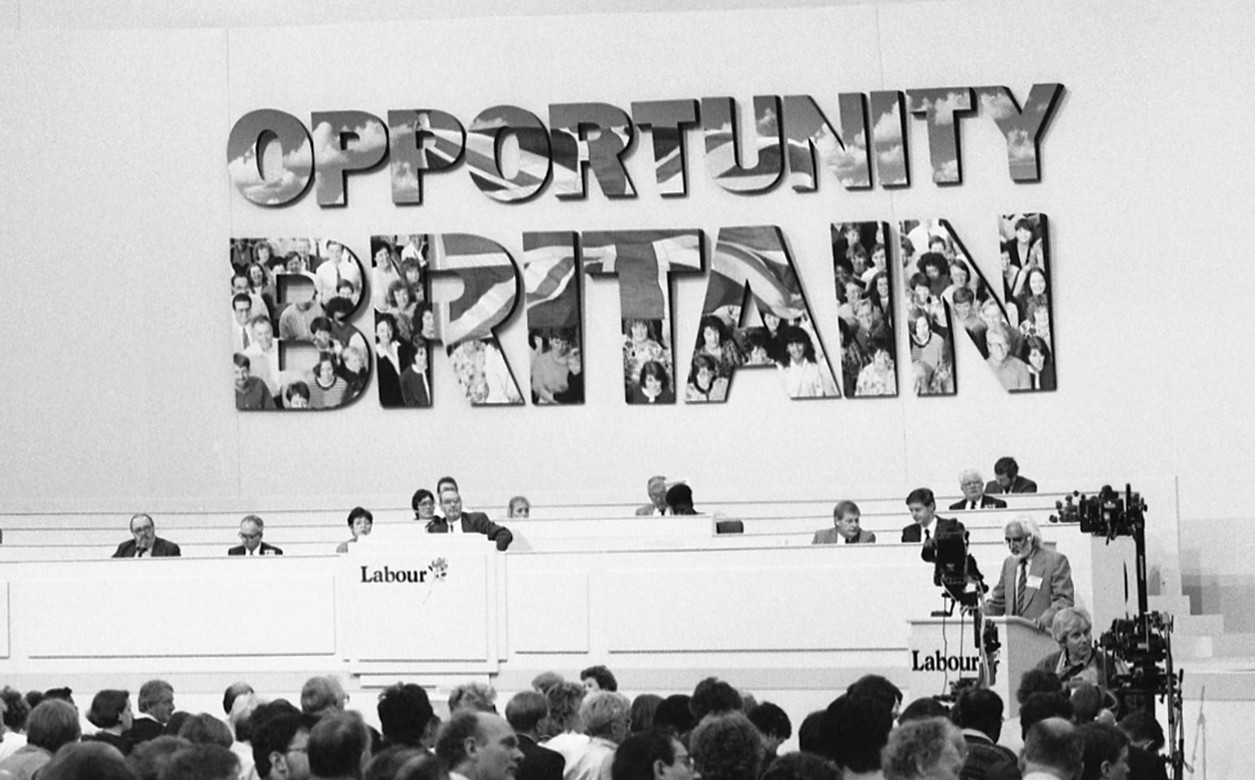 A panel on people sat in a row with a sign behind them which reads Opportunity Britain.