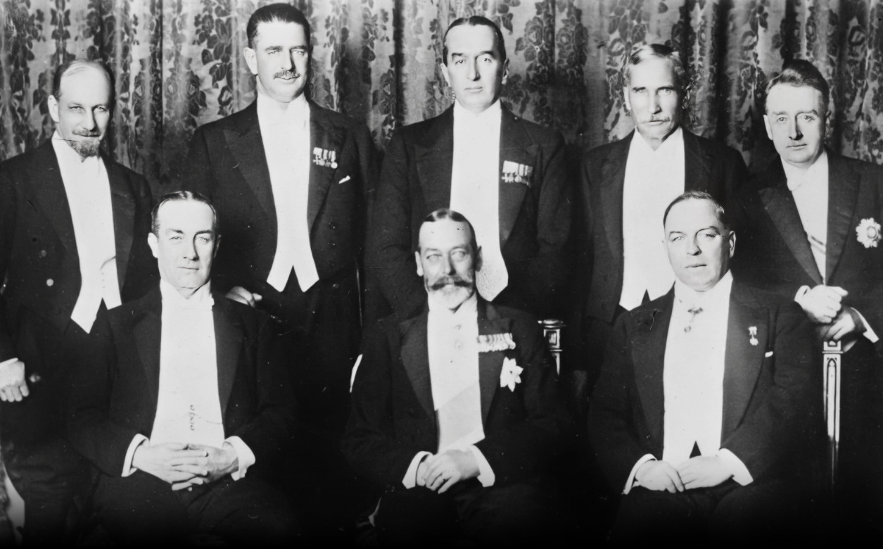 A black and white image of eight men wearing suits. WT Cosgrave with WS Monroe of Newfoundland, JG Coates of New Zealand, Stanley Bruce of Australia, JB Hertzog of the Union of South Africa, Stanley Baldwin of the United Kingdom, King George V, and Mackenzie King of Canada at the imperial conference of 1926.