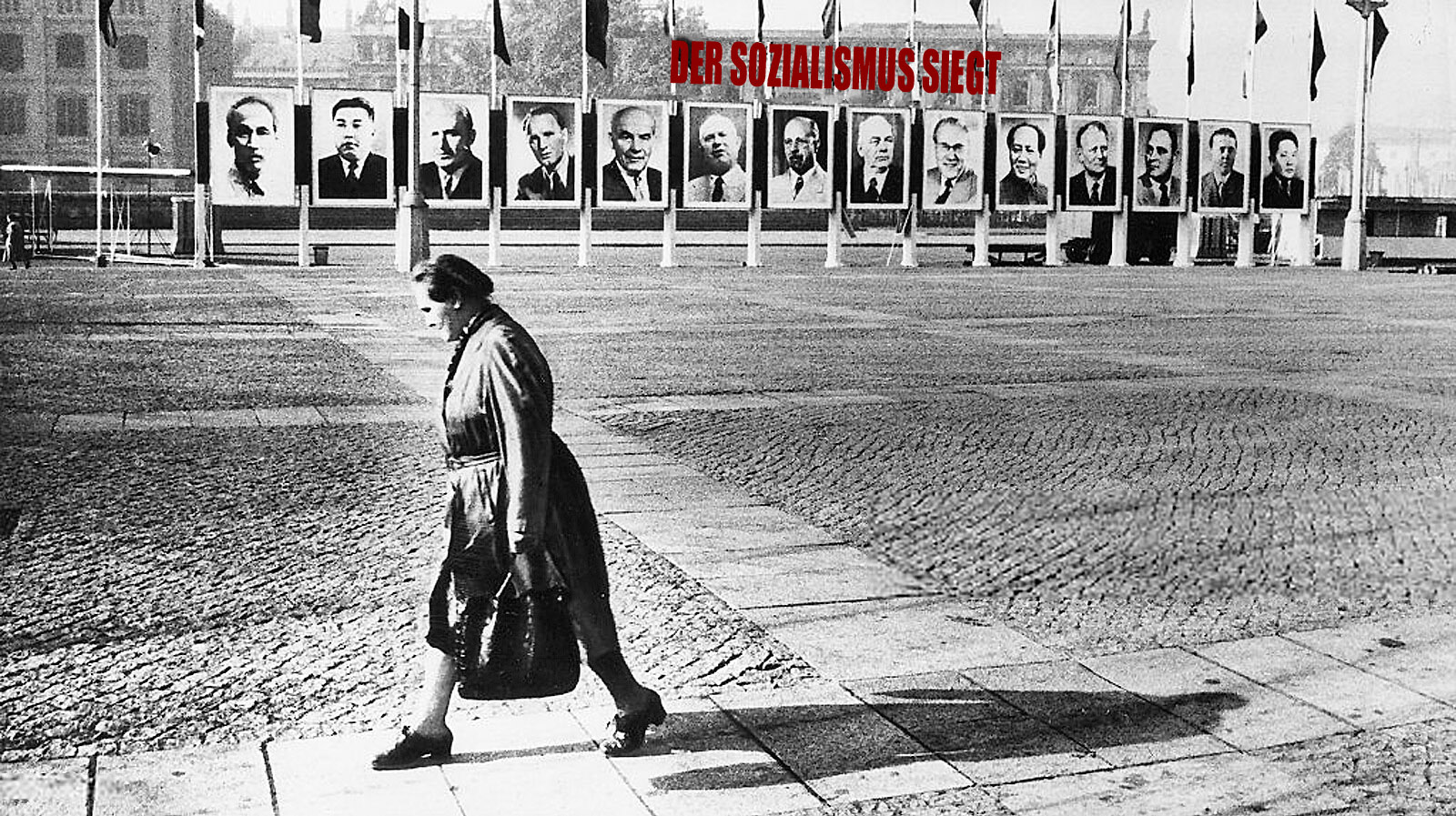 Women walking in front of East German public square festooned with propaganda posters, circa 1970s
