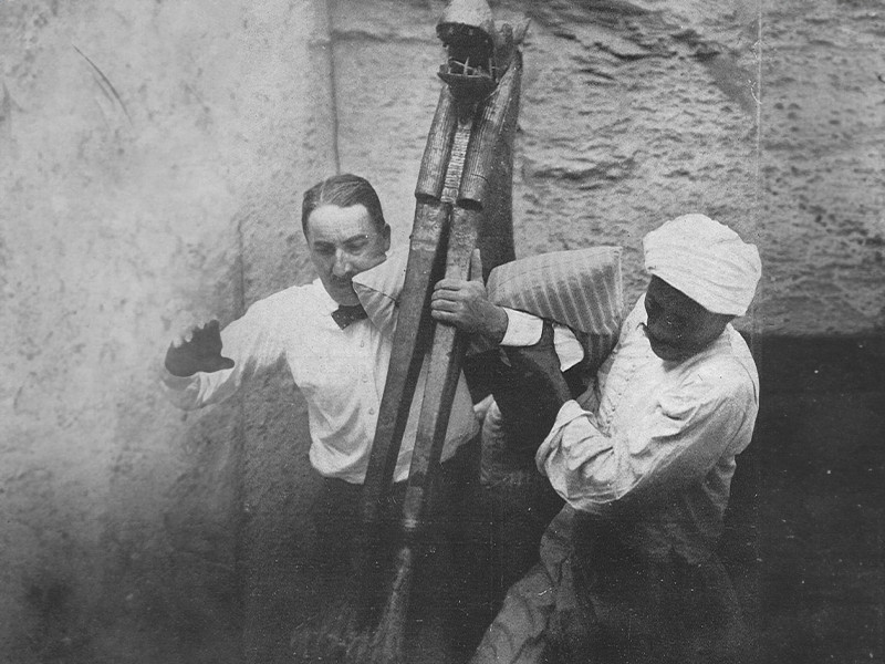 Black and white photograph of Howard Carter and another man removing an artefact from Tutankhamun's tomb.