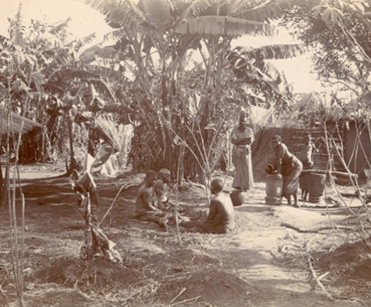 A photograph of people sat beneath trees in the village of Zomba in Southern Malawi.