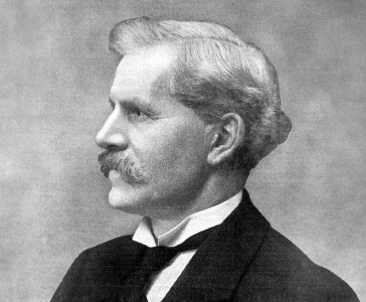 A black and white profile of Ramsay MacDonald, who has white hair and a prominent moustache.