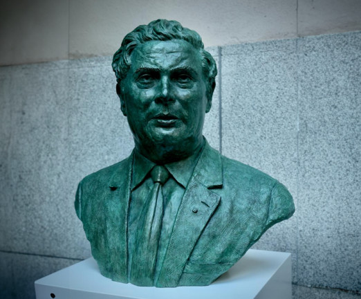 A green metal bust of John Hume.