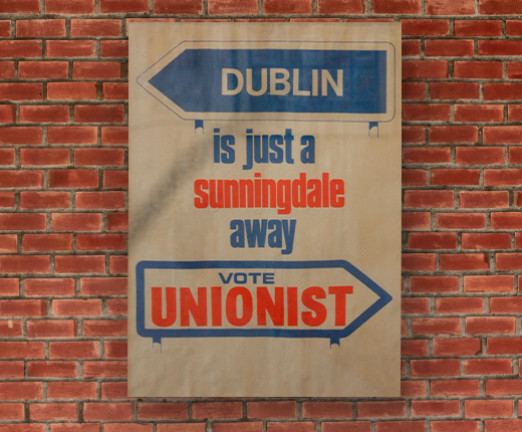 A poster hanging on a brick wall. the poster says Dublin is just a sunningdale away. Vote Unionist.