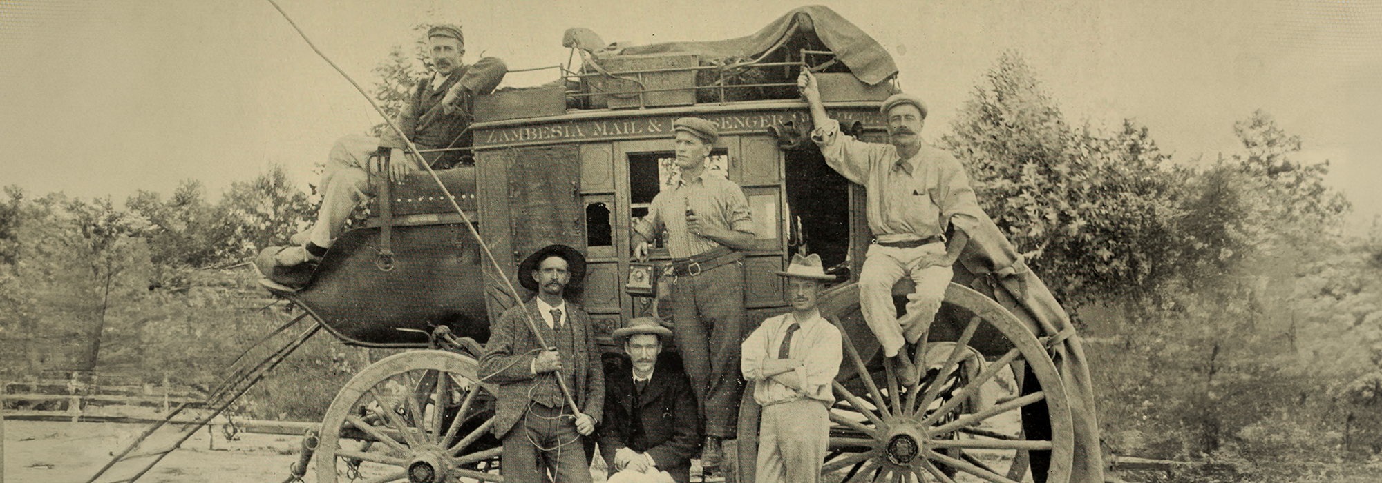 Six men stood and sat around a wagon - the first run of the Zambesia Mail and Passenger Company stage coach between Salisbury (now Harare) and Umtali (now Mutare), Southern Rhodesia (now Zimbabwe).