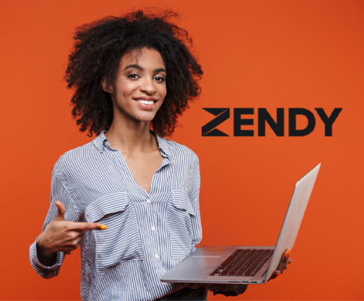 A woman with brown afro hair and a white and blue stripey shirt stands with a laptop in her hand. She is pointing at the screen and smiling at the camera. The word Zendy appears next to her. She stands against an orange background.