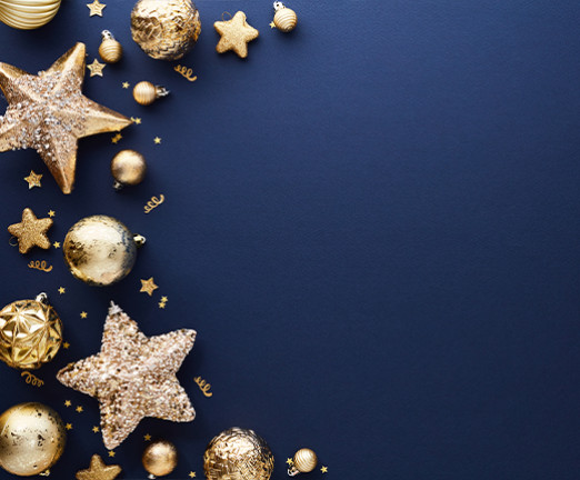 A navy blue background with a crescent shaped organisation of festive decorations, including stars, baubles, and glitter.