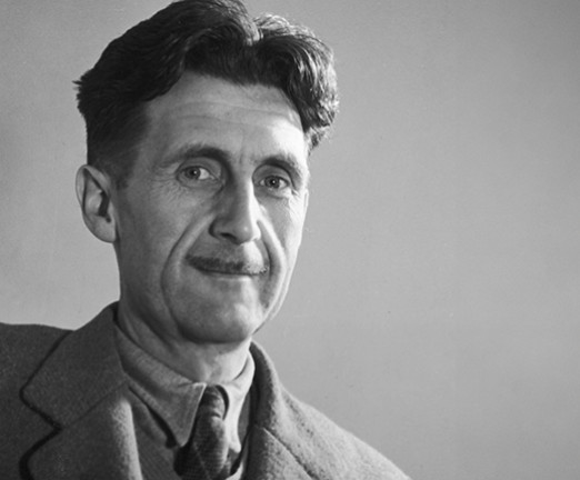 A black and white photograph of George Orwell, a man with dark hair, a moustache, and smart dress.