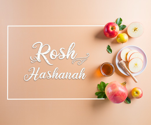 A neutral background with text that says Rosh Hashanah. There are various fruits to the right of the text.
